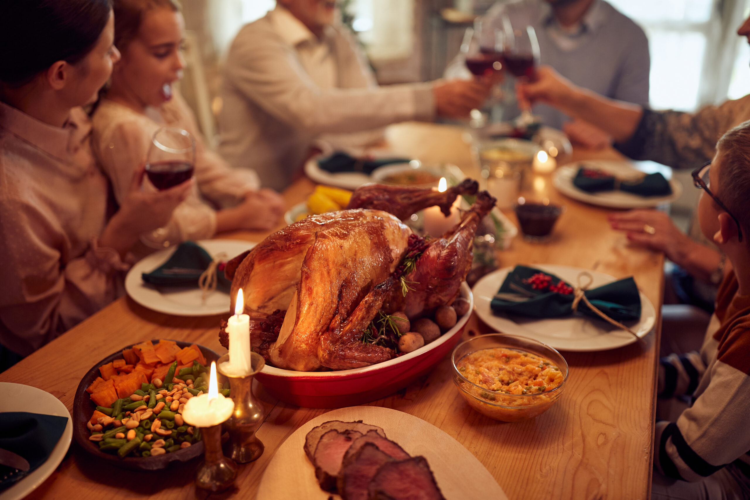 Close-up of traditional Thanksgiving turkey with family gathered around dining table,